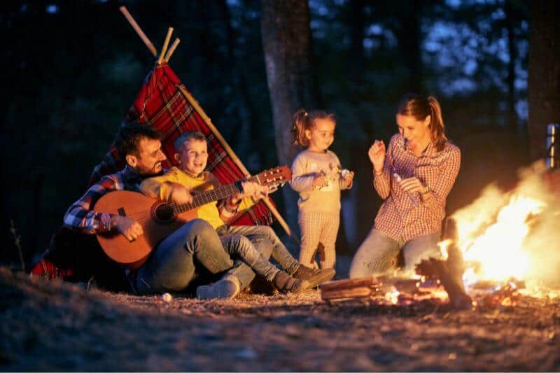 family sitting by a bonfire roasting marshmallows, Autumn scene