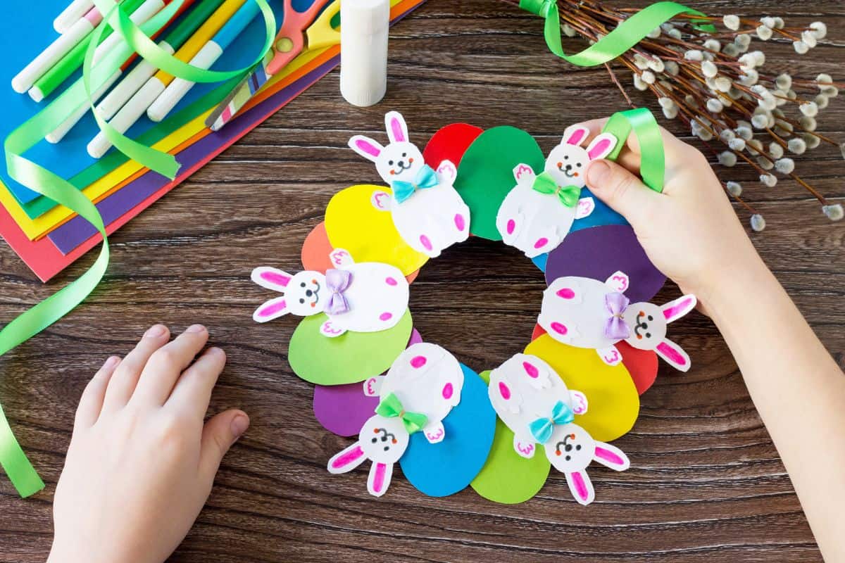 Paper Easter wreath with crafts supplies on a wooden table.