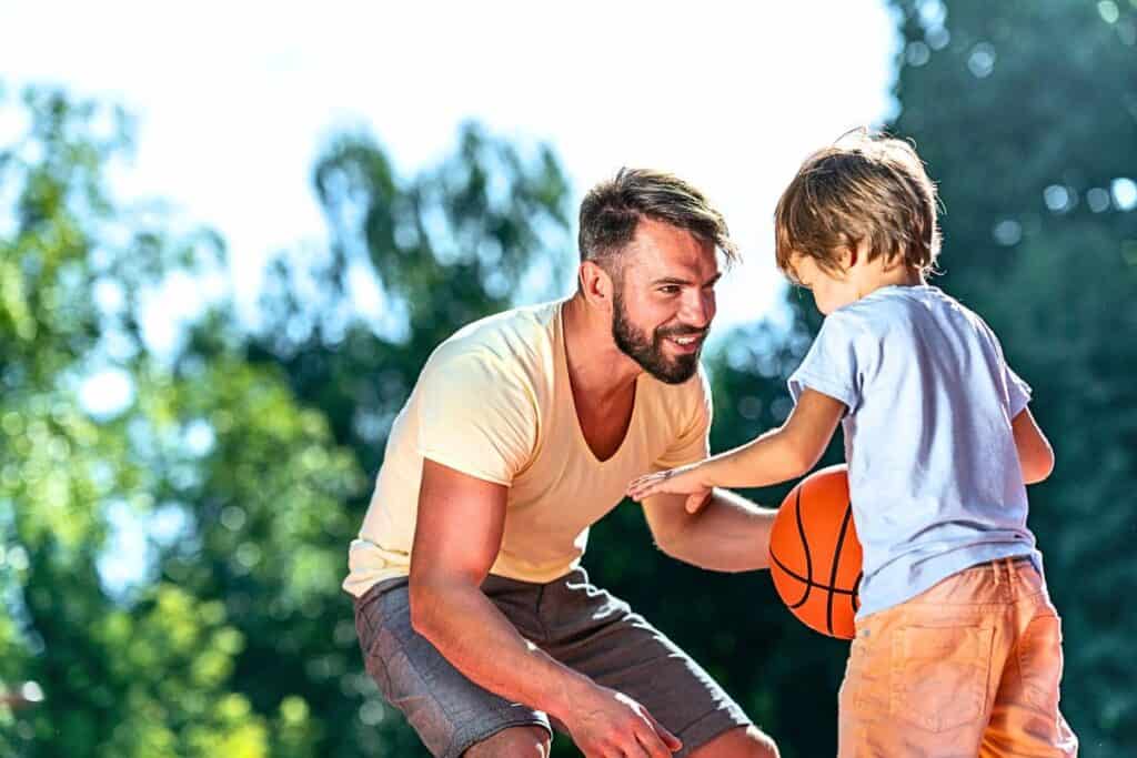 Father and son playing basketball in the garden.