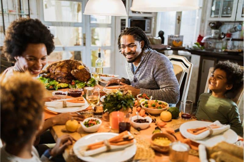 family of 4 having Thanksgiving dinner with a turkey on a festive table