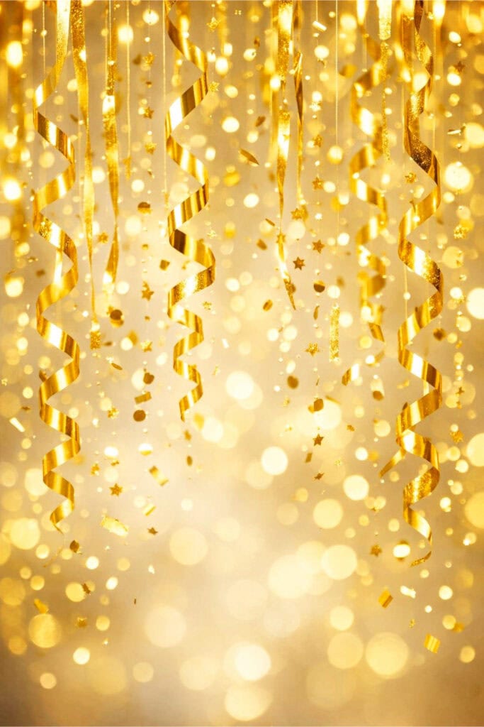Gold confetti hanging decorations suspended against a softly blurred background creating a festive atmosphere.