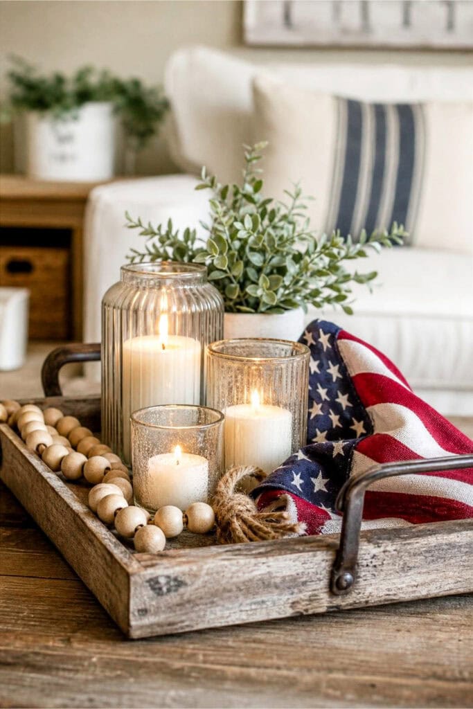 A wooden coffee table tray holding lit candles, wooden beads, and a small fabric flag in a cozy living room setting.