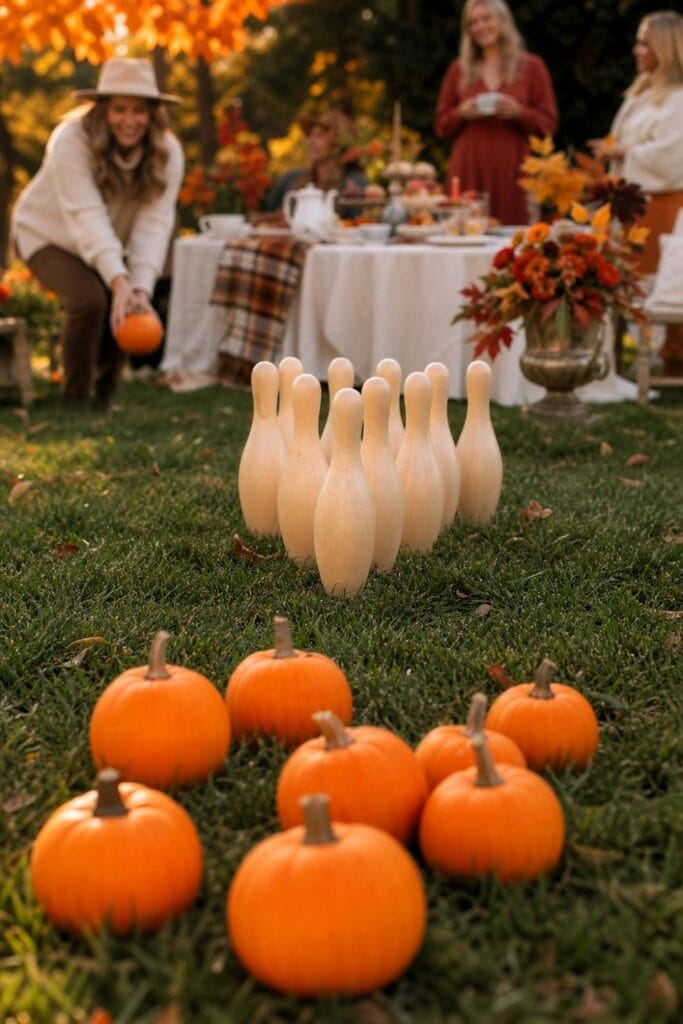 Pumpkins arranged as bowling balls beside pins at an outdoor autumn tea party.